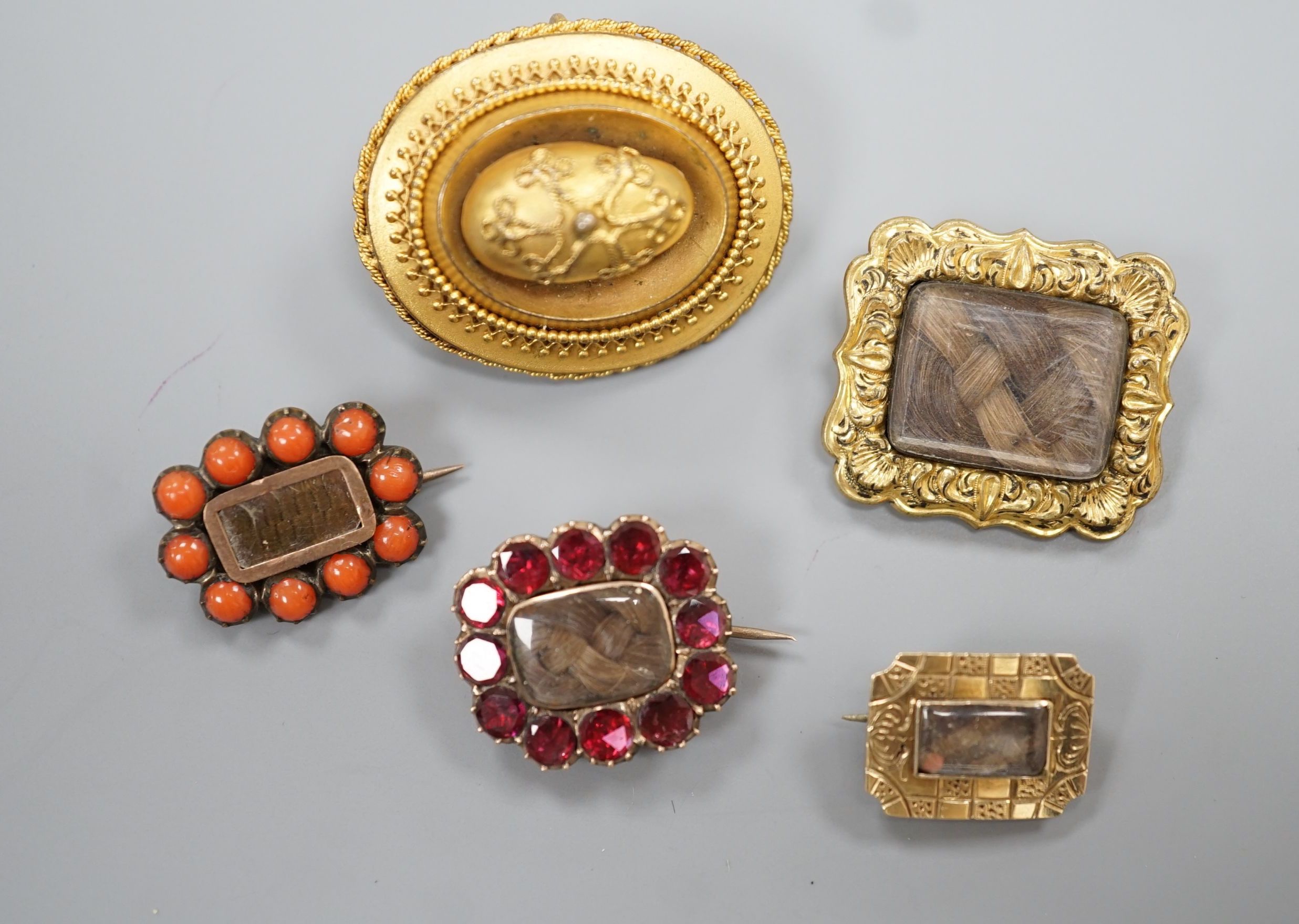 Two 19th century gilt metal and plaited hair set mourning brooches, two other mourning brooches and an oval pinchbeck brooch, largest 34mm.